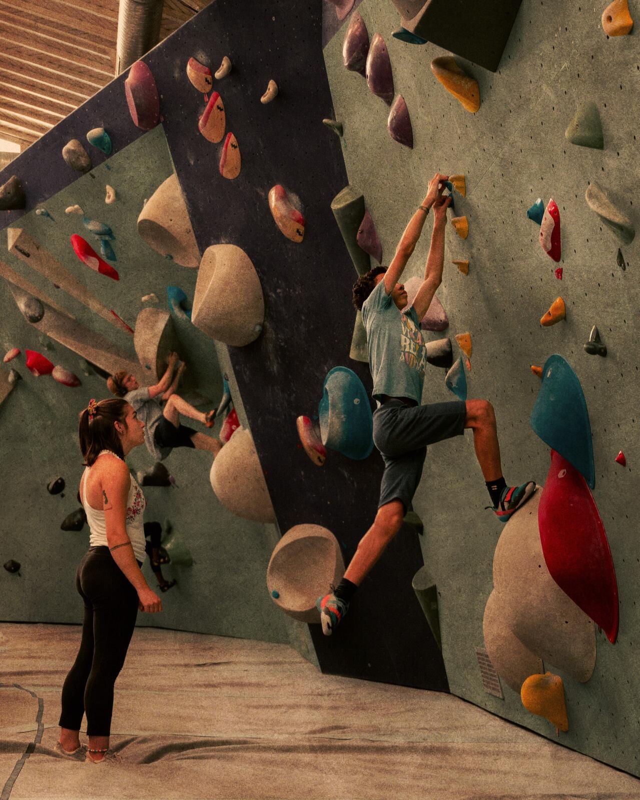 Moniteur qui équipe un enfant d'un baudrier pour une activité de grimpe encordée