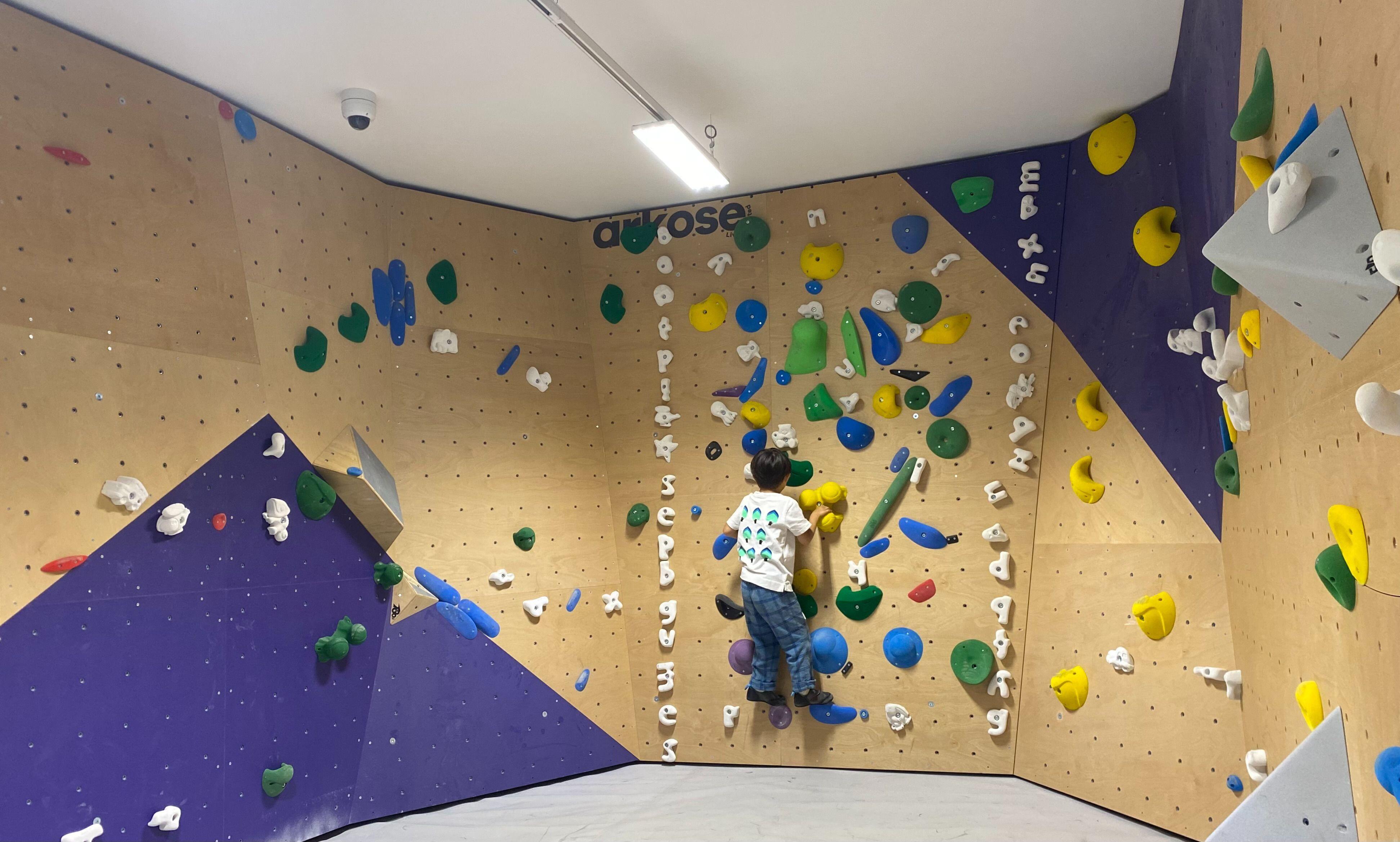 Mur d'escalade de bloc avec prises colorées dans une salle Arkose